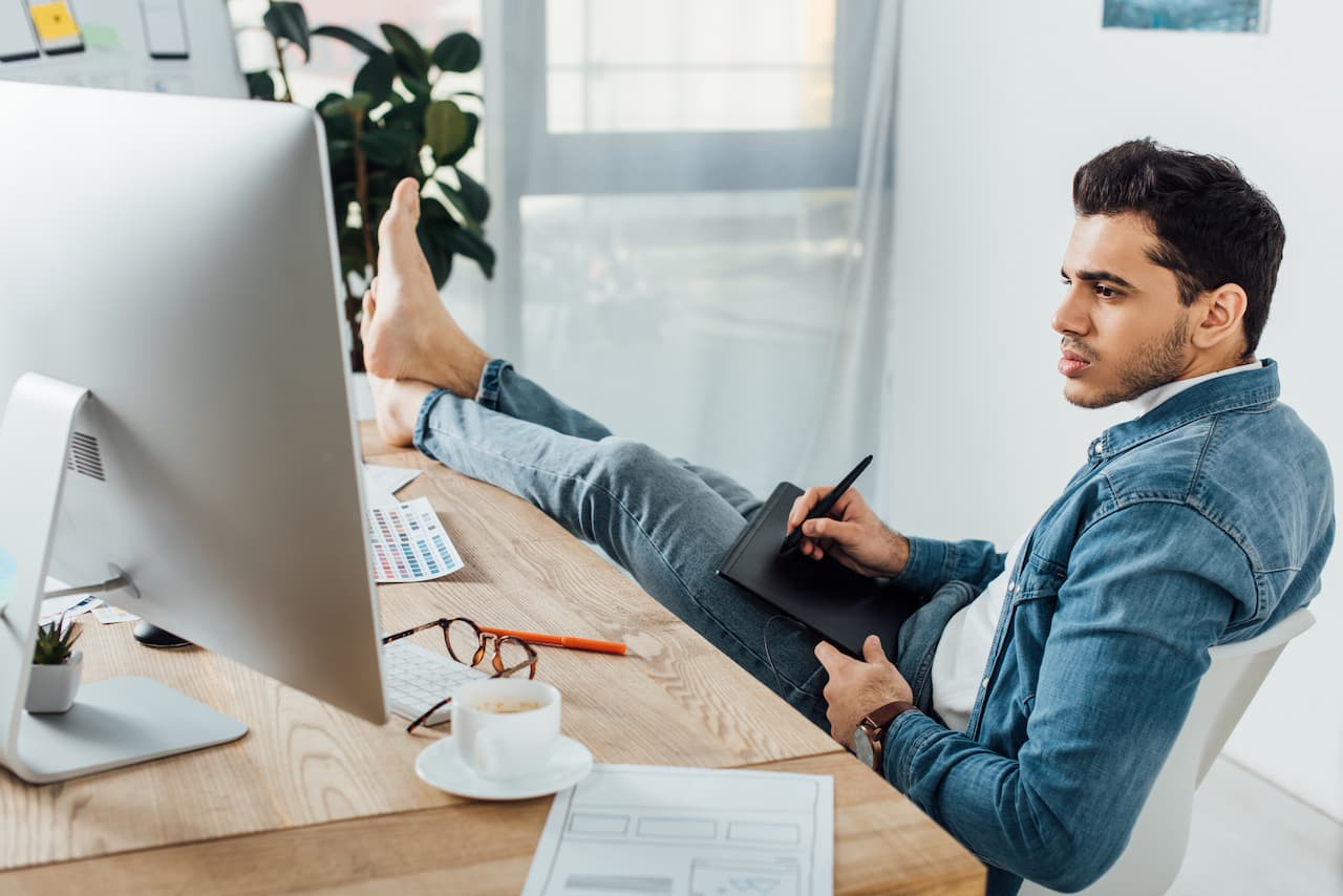 A man sitting at a desk with his feet up, engrossed in work