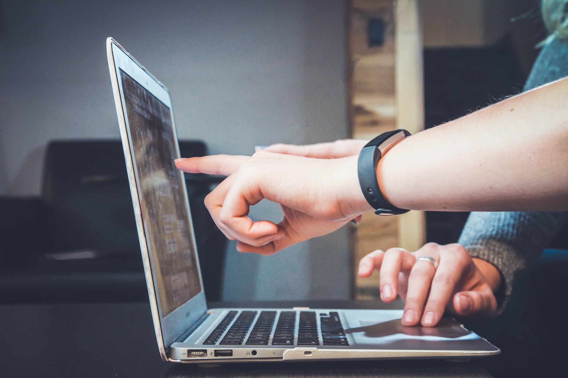 A person pointing at a laptop computer, indicating focus or interest