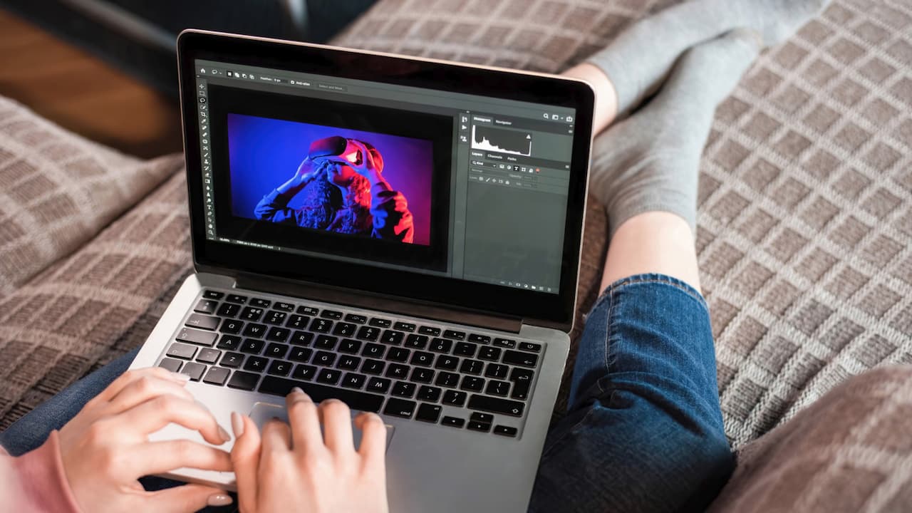 A person sitting on a couch with a laptop using Photoshop